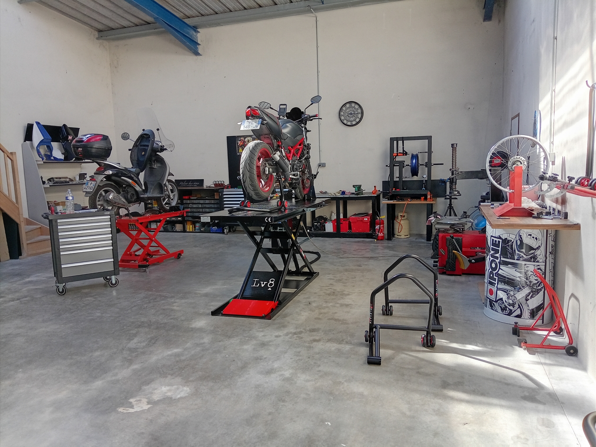 Vue d'ensemble de l'atelier ROUBY SEB MOTO : moto sur pont élévateur, outillage spécialisé et zone de travail.