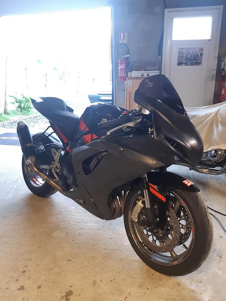 Moto équipée de son carénage polyester piste brut, avant peinture, dans l'atelier.