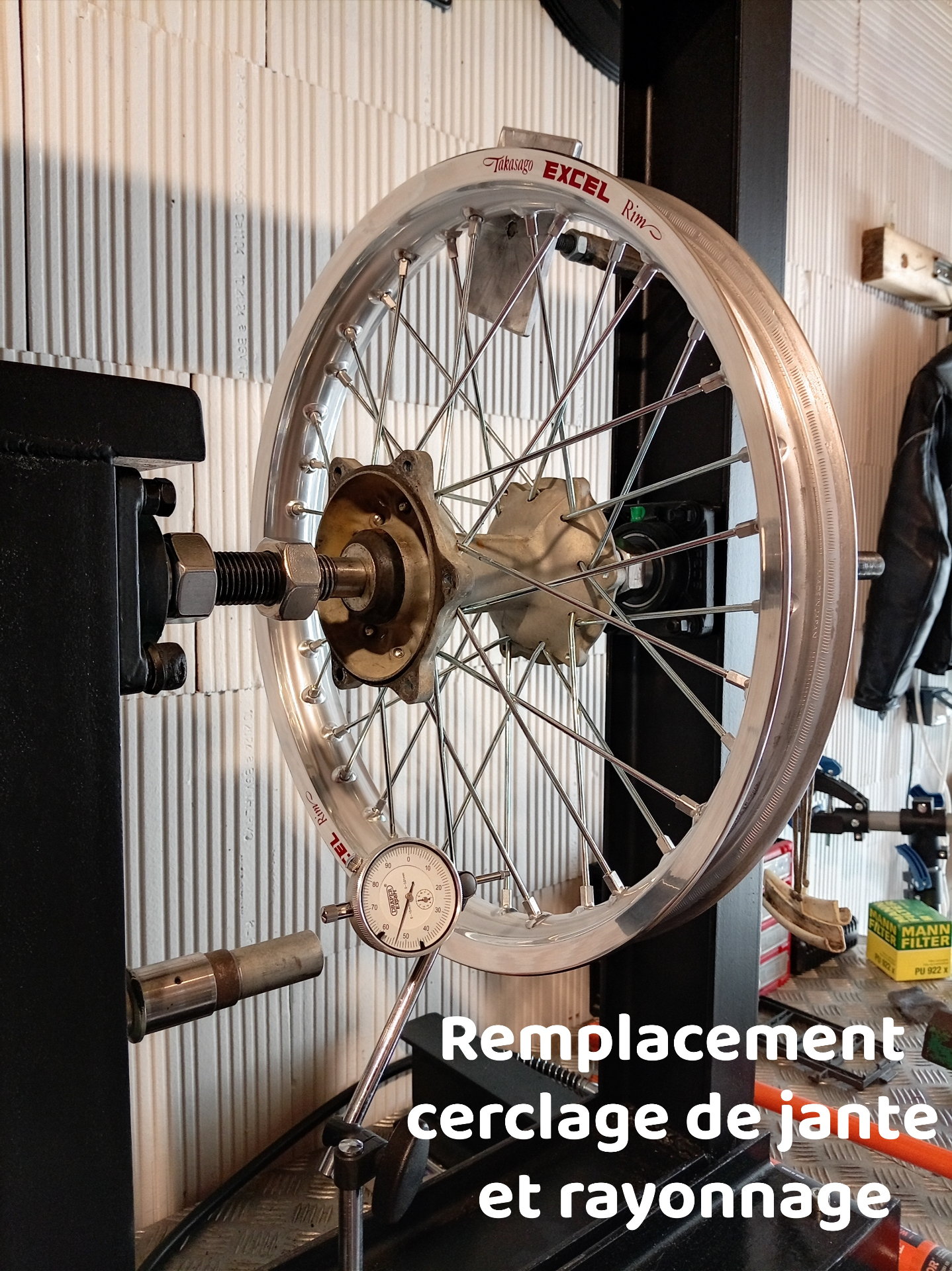 Roue de moto cross montée sur banc de dévoilage avec comparateur, en cours de rayonnage à l'atelier ROUBY SEB MOTO.
