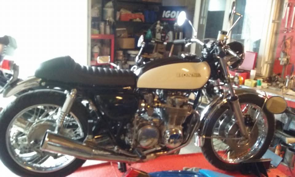 Honda 500 Four de 1974 entièrement restaurée en café racer, réservoir crème et noir, moteur poli, échappement chromé, dans l'atelier.